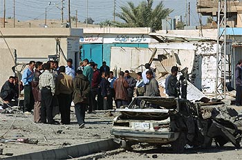 Un grupo de curisosos iraquíes, entre los restos de la comisaría atacada.