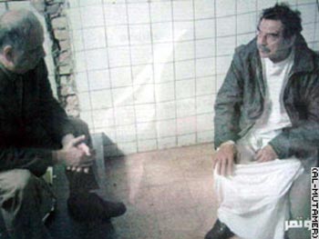 El ex presidente iraquí aparece vestido con ropa tradicional árabe y un anorak.