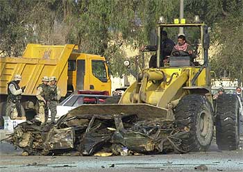 Un  bulldozer  retira coches calcinados del lugar donde ayer estalló un todoterreno cargado con 500 kilos de explosivo.