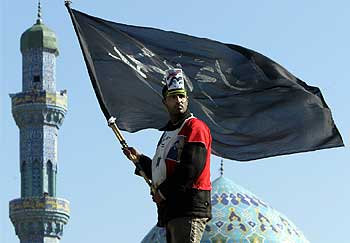 Un chií enarbola la bandera negra del profeta Mahoma durante la manifestación de hoy.