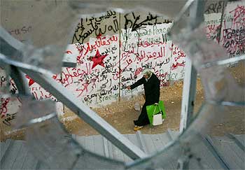 Una mujer palestina, vista a través de una ventana, mientras camina junto al muro, de ocho metros de altura.