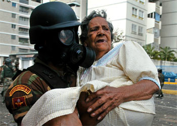 Un policía auxilia a una anciana afectada por los gases lacrimógenos durante los disturbios en Caracas.