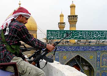 Un militante chií vigila, rifle en mano, la mezquita del imán Alí en la ciudad santa de Nayaf.