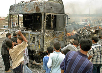 Niños iraquíes, entre los restos del convoy de EE UU atacado hoy en Bagdad.
