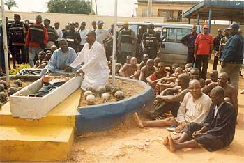 La policía muestra, ante la comisaría de la ciudad de Okija, a los arrestados y parte de los restos hallados.