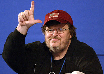 El cineasta Michael Moore responde desde la tribuna de prensa con el gesto de 