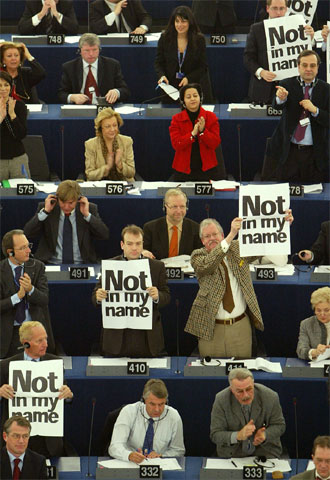 Diputados del Europarlamento aplauden el resultado de la votación mientras otros muestran su rechazo con pancartas que rezan 