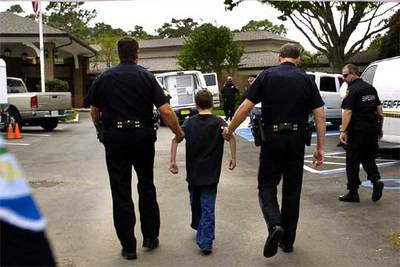 Dos agentes conducen a dependencias policiales a un niño detenido por intentar entrar en el hospital donde agoniza Schiavo.