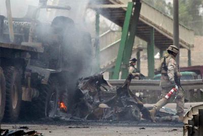 Un soldado estadounidense, junto a los restos de un coche bomba en Bagdad.