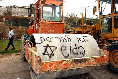 Un policía israelí pasa ante vehiculos de construcción con pintadas contra el Plan de Desconexión al sur de la franja.