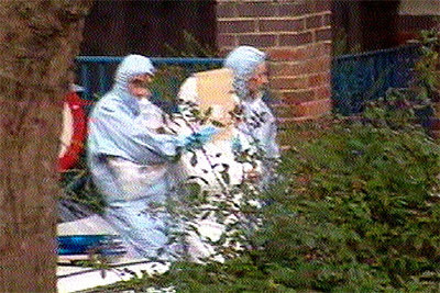 Dos agentes de policía escoltan a un detenido, en el centro y con el rostro cubierto, tras su arresto en Notting Hill.