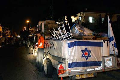 Una colona espera junto a un camión con las pertenencias de su familia para abandonar el asentamiento de Neve Dekalim.