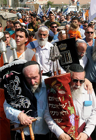 Los colonos de Netzarim abandonan la sinagoga con los cuatro rollos de la Torá y el rabino Tawui al frente.