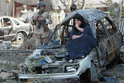 Una mujer iraquí, sentada en uno de los vehículos destrozados por la explosión de dos coches bomba en Bagdad.
