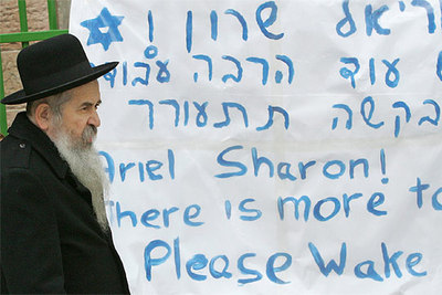 Un judío ultraortodoxo camina ante una pancarta de apoyo a Ariel Sharon colocada en la puerta del hospital Hadassah.