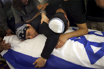 La madre de una de las nueve víctimas mortales del atentado suicida de ayer en Tel Aviv abraza el ataúd de su hijo.