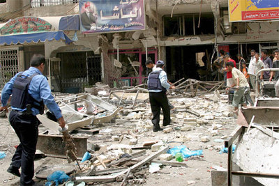 Varios policías iraquíes inspeccionan la zona en la que ha explotado un coche bomba, situada junto a una de las entradas de la protegida 