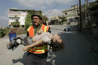 Un miembro de la Defensa Civil lleva en sus brazos a una niña rescatada del edificio destruido