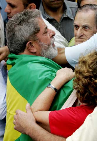 Lula, envuelto en una bandera de Brasil, saluda a sus seguidores  tras depositar su voto.