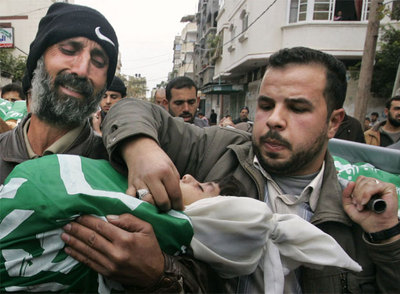 El padre de las cinco niñas Balusha lleva el cadáver de una de ellas durante el funeral en el campo de refugiados de Jabalia.