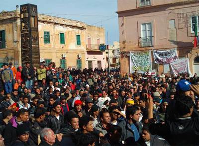 Decenas de habitantes de Lampedusa, acompañados por inmigrantes llegados a la isla del sur de Italia, protestan frente al Ayuntamiento de la localidad contra la decisión del Gobierno italiano de sustituir el actual centro de acogida por un Centro de Identificación y Expulsión.