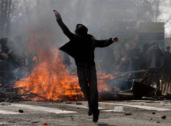 Un manifestante arroja una piedra contra la policía