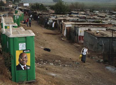 Una mujer observa unos baños públicos donde hay publicidad electoral de Jacob Zuma en Johanesburgo.