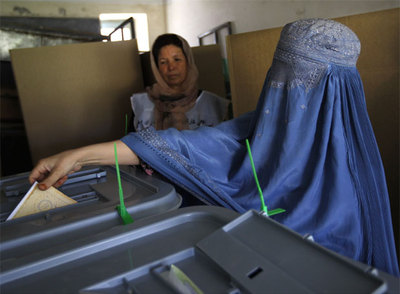 Una mujer afgana vestida con una  burka  deposita su voto en la urna en un colegio de Kabul.