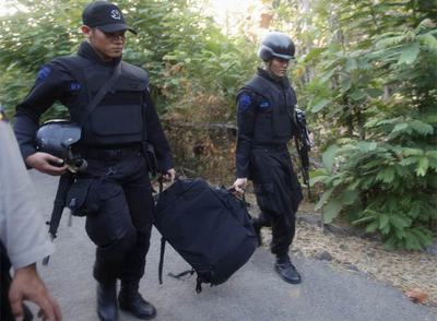Dos policías cargan material antes de realizar el asalto a una casa en Indonesia.