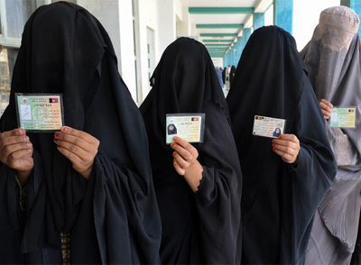 Mujeres afganas ataviadas con  burkas  enseñan sus carnés de electoras mientras hacen cola para votar en Kandahar, el pasado 20 de agosto.