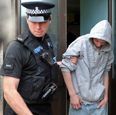 Un policía traslada al adolescente que lanzó el huevo contra David Cameron.