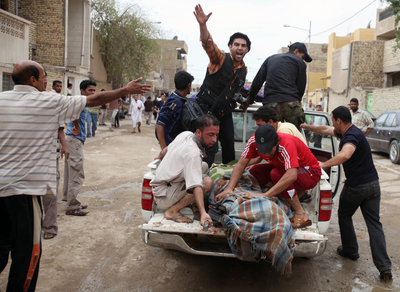 Un grupo de personas lleva a uno de los heridos en los atentados de Irak