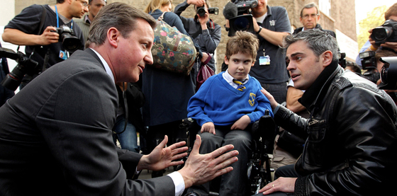 El líder de los conservadores británicos, David Cameron (izquierda), gesticula en presencia de Jonathan Bartley (derecha) y su hijo de siete años, afectado de espina bífida. Bartley, ex colaborador del  premier  John Major, ha reprochado al candidato  tory  en presencia de numerosas cámaras su plan de creación de nuevas escuelas especiales, lo que considera una política de segregación.