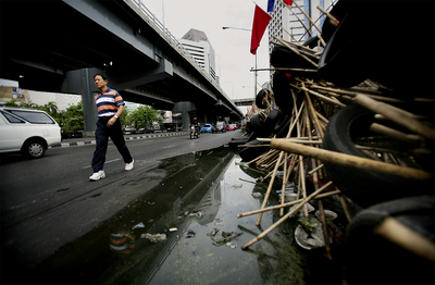 Un hombre bordea las empalizadas que limitan el campamento de los  camisas rojas  en el corazón financiero de Bangkok.