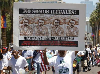 Un hispano sostiene una pancarta en contra de la nueva ley antiinmigración durante una protesta en Phoenix, Arizona.