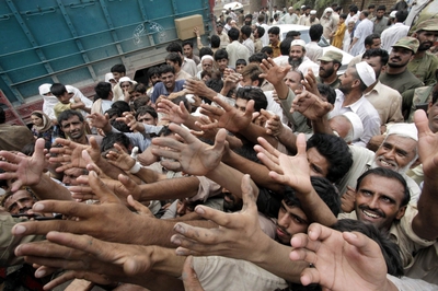 Paquistaníes afectados por las inundaciones tratan de coger alimentos durante un reparto de ayuda humanitaria.