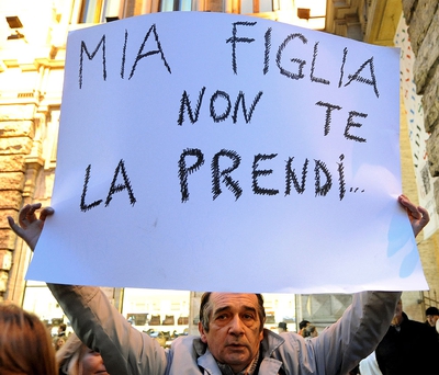 Un manifestante durante una protesta contra el primer ministro Silvio Berlusconi muestra una pancarta que dice: 
