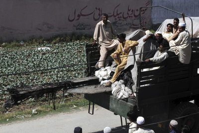 Paquistaníes subidos a bordo de un camión que transporta los restos de un helicóptero del ejército de EEUU que se estrelló durante la operación.