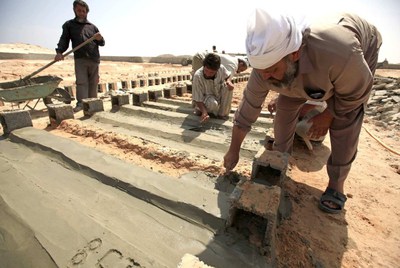 Tres voluntarios aplican cemento a las tumbas de soldados leales a Muammar Gaddafi que han sido enterrados en un cementerio de Misrata.
