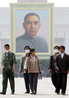Un grupo de turistas, con mascarilla ante un retrato de Sun Yat-Sen en una desierta plaza de Tiananmen, en Pekín..