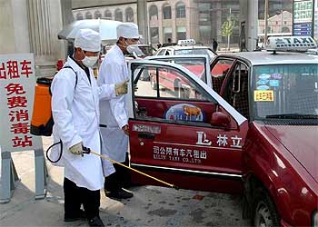 Dos trabajadores desinfectan un taxi en una gasolinera de Zhengzhou, en la provincia china de Henan.