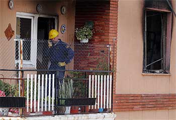 Un policía habla por el móvil en la terraza del piso incendiado en el que han muerto la mujer y los dos niños.