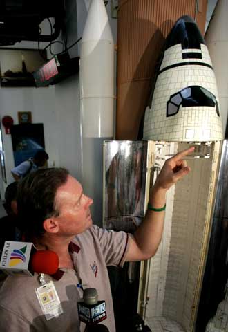 Un portavoz de la NASA explica sobre una maqueta del  Discovery  el lugar de donde se ha desprendido una pieza.