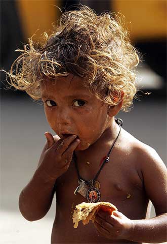 Un niño se alimenta de la basura que ha recogido en el suelo de las calles de la ciudad india de Nueva Delhi.