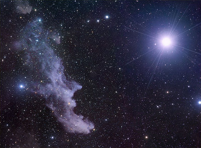 La supergigante azul Rigel, en la constelación de Orión. A la izquierda se encuentra la Nebulosa de la Cara de Bruja, compuesta de gas y polvo, que vemos porque refleja la luz de Rigel. En la imagen también hay otras muchas estrellas de diferentes colores.