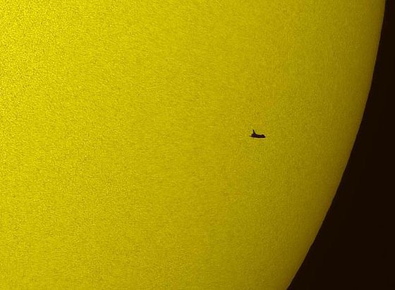 La silueta del transbordador 'Atlantis' recortada contra el Sol en una imagen tomada desde la Tierra