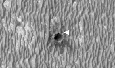 El robot  Opportunity , señalado con la flecha, junto al borde de un cráter en una foto tomada desde la nave  MRO .