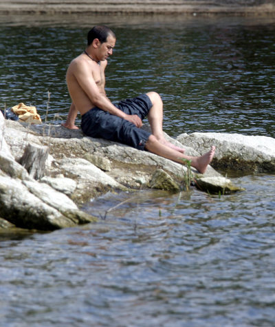 Un visitante toma el sol junto al embalse de Valmayor, un sitio donde no se permite bañarse.